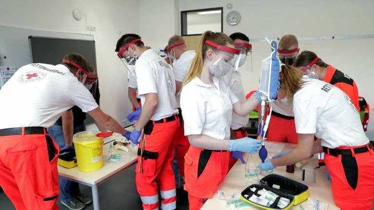 Rettungssanitäter im Unterricht mit geringem Abstand und Faceshield